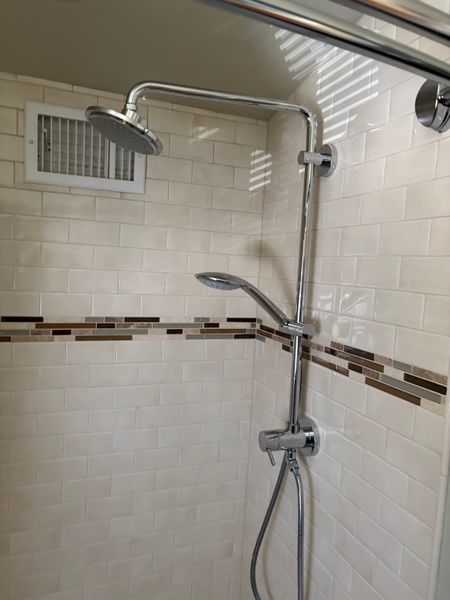 Finished chrome shower system with rain head and hand shower in a subway tile shower in Baltimore, MD — ProStream Plumbing