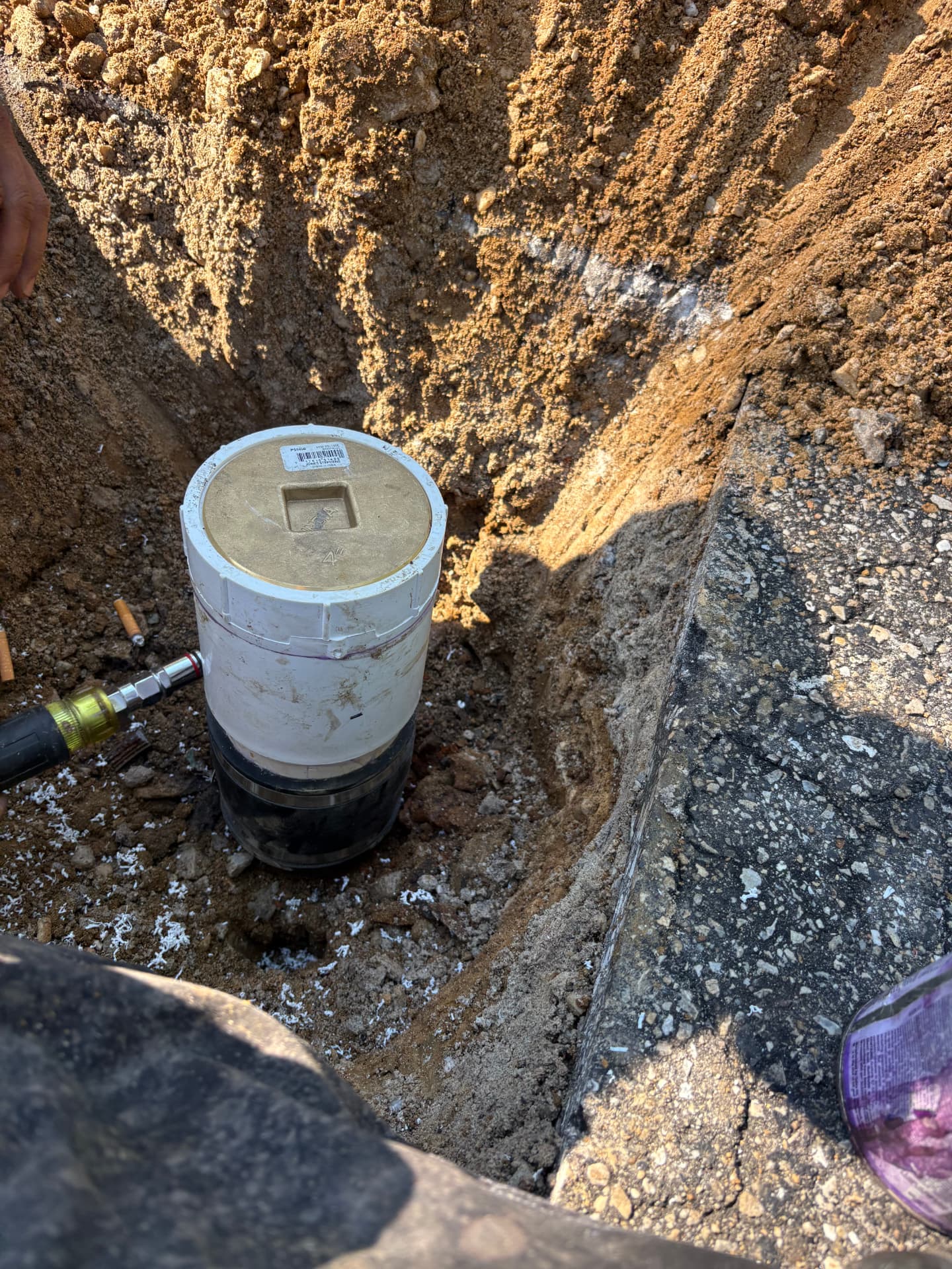 New sewer cleanout assembly with brass plug set in a driveway excavation in Baltimore, MD — ProStream Plumbing