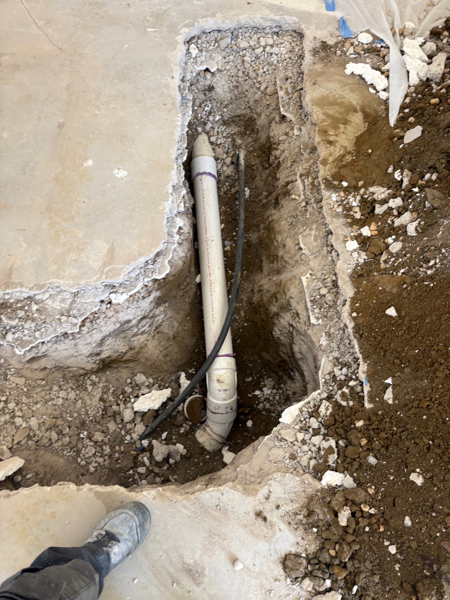New PVC drain line in a cut concrete basement floor trench in Baltimore, MD — ProStream Plumbing
